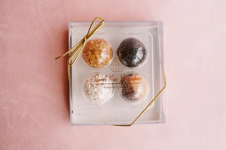 A box of eight assorted colorful Brazilian bon bons, covered in yellow, pink, brown, and white toppings.