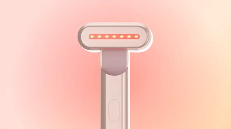 SolaWave Wand in rose gold against a red and orange background