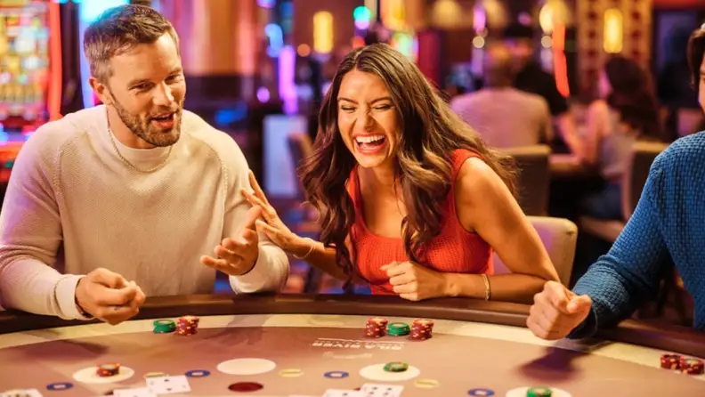 Group of three people happily playing Blackjack inside a casino