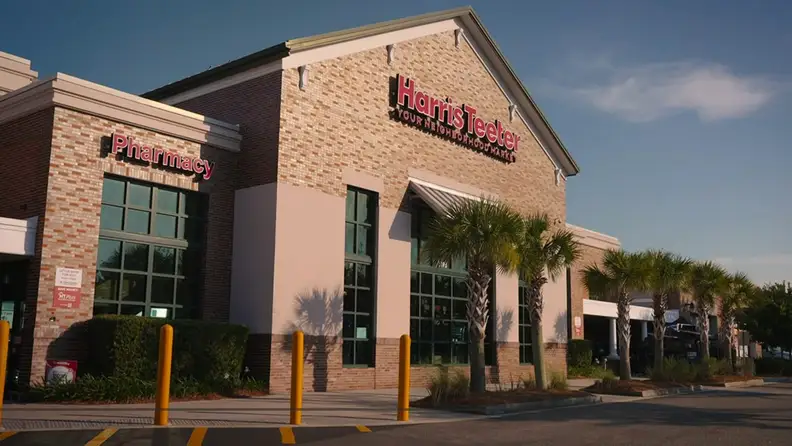 Harris Teeter storefront with pharmacy sign and palm trees lining the entrance
