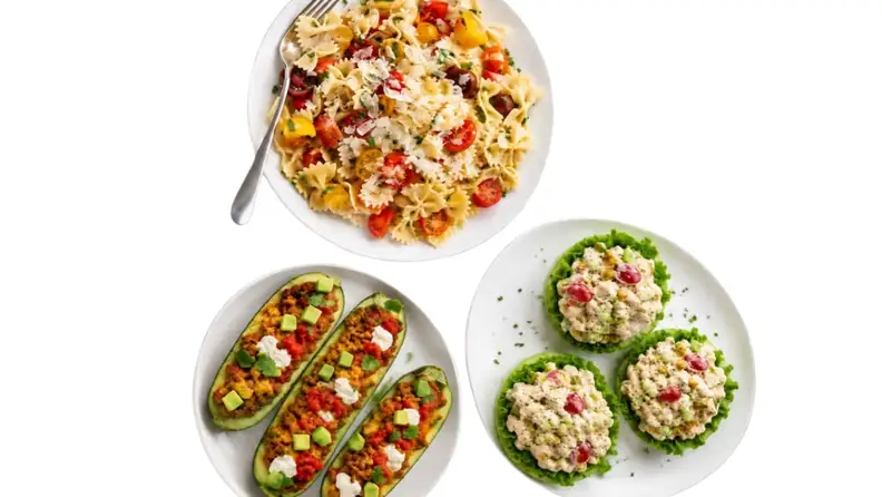Deli plates of pasta salad, stuffed zucchini boats, and chicken salad