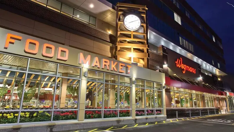 Wegmans storefront at night with clock tower and Food Market sign