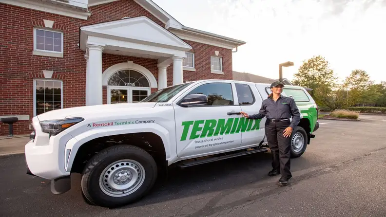 Technician standing by the vehicle parked in front of a building
