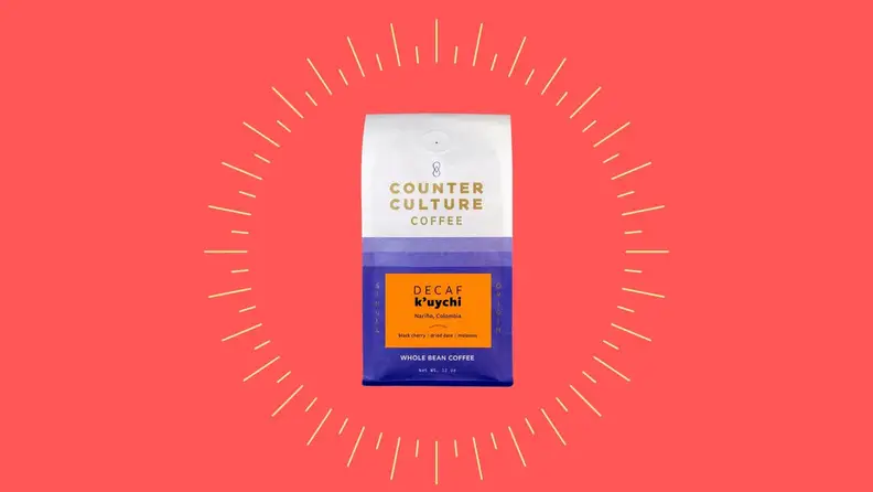 A bag of decaf coffee against a bright pink background.