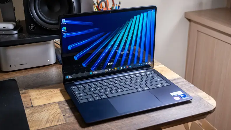 Dell 14S (DS14260) laptop open displaying a blue abstract design on screen, atop a wooden surface.