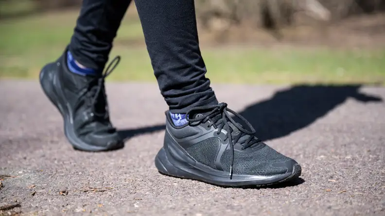 A close-up of the black Lululemon sneakers while walking on a sidewalk