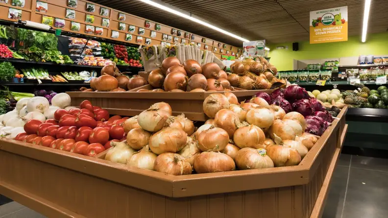 Produce display of onions, tomatoes, and organic vegetables