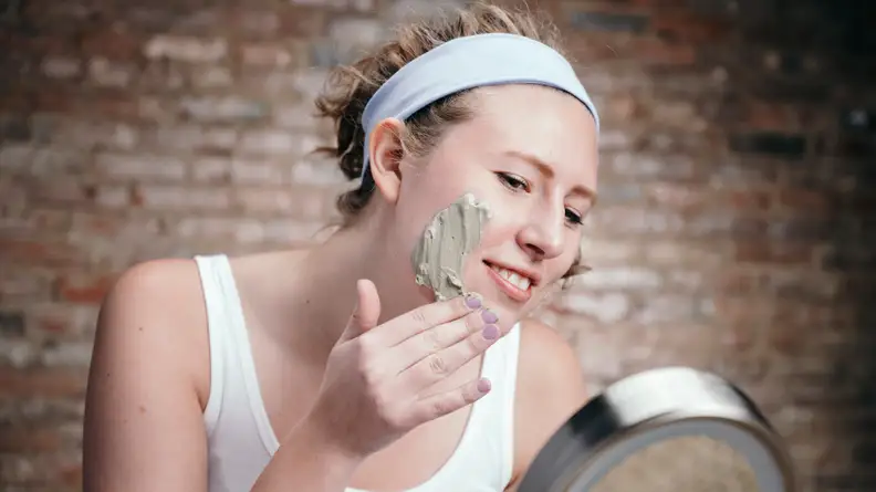 A photo of a woman applying a face mask.