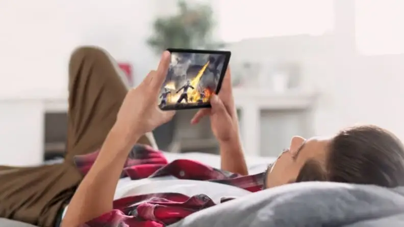 Man lying on bed, watching Samsung tablet.