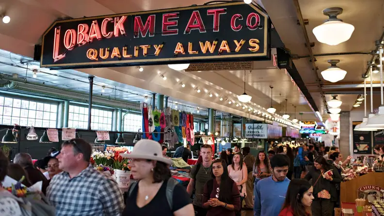 Neon "Loback Meat Co." sign above a bustling Pike Place Market crowd