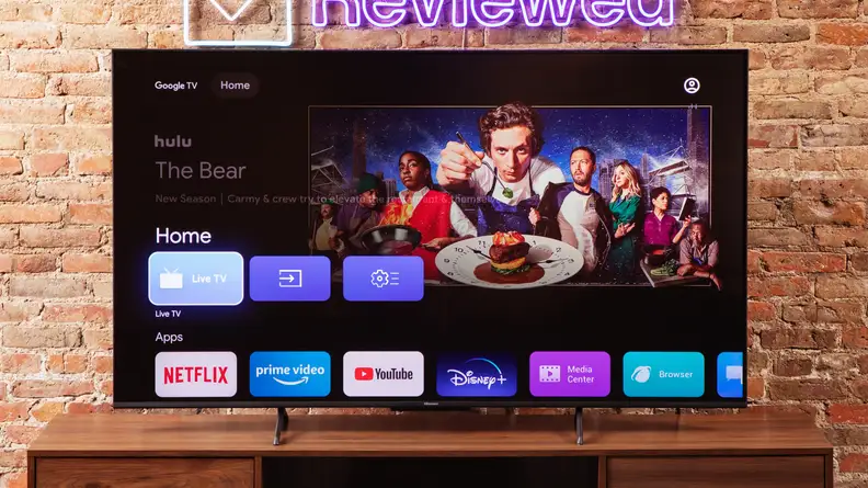 The Hisense U6K Mini-LED TV on a table with a brick background.