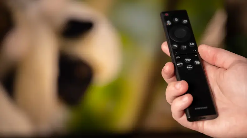 A close-up of someone's hand holding the Samsung Solar Cell remote control