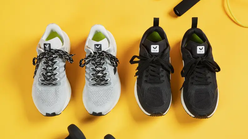 Two pairs of running shoes surrounded by gym equipment.