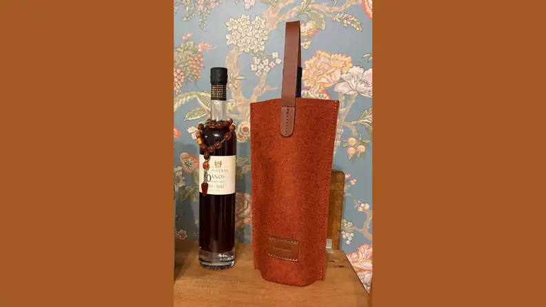 A merino wool felt bag holding a bottle of wine