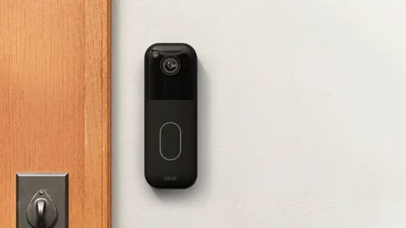 A video doorbell mounted to a wall next to a front door