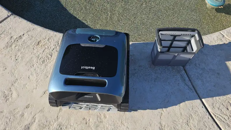 The Beatbot AquaSense Pro robot pool vacuum sits near a pool.