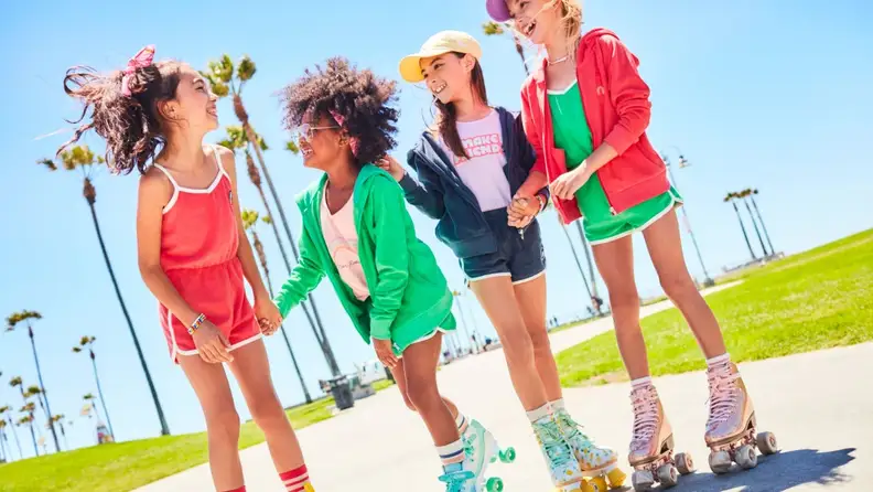 A group of girls wear colorful clothes as they rollerskate