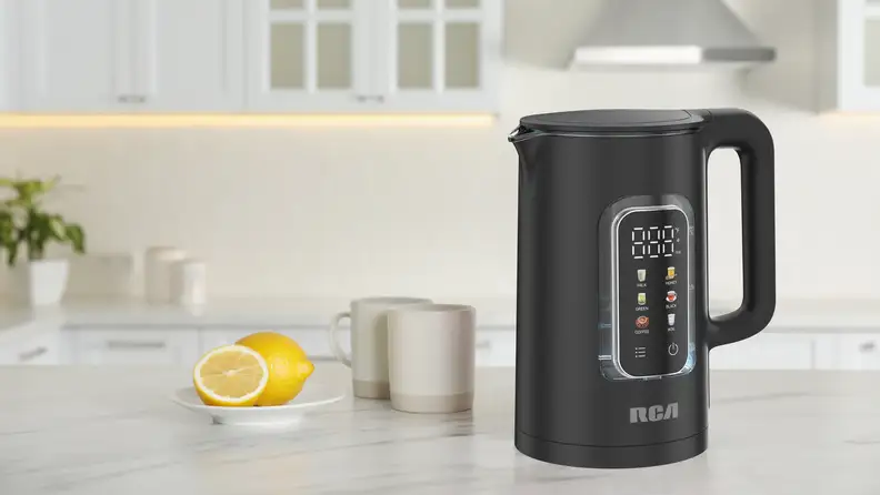 The RCA electric kettle on a white counter with mugs.