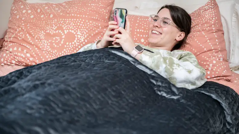 a woman lies under the gravity blanket in bed