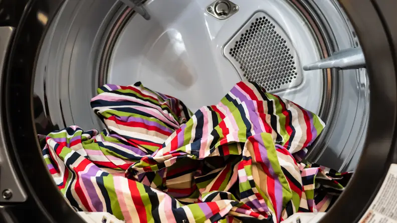 A close-up of the LG WashTower's dryer drum, with a colorful blanket resting at the bottom for scale and a pop of color.
