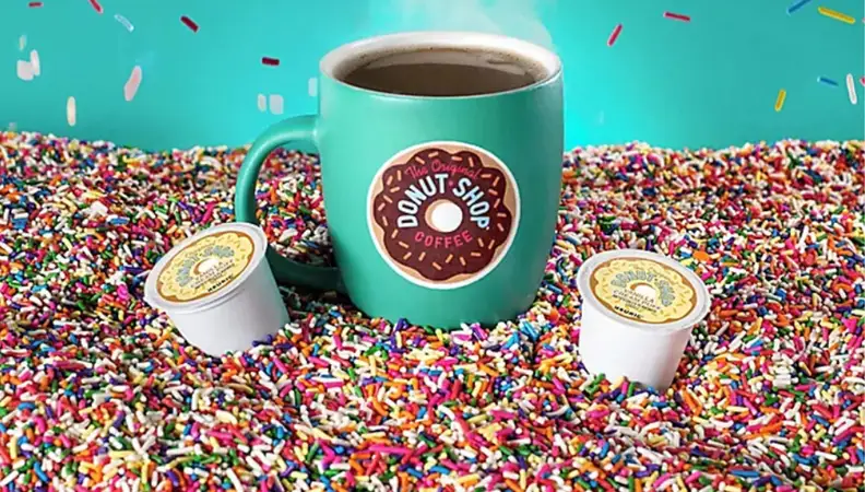 A bright teal coffee mug, surrounded by a sea of multicolored sprinkles.