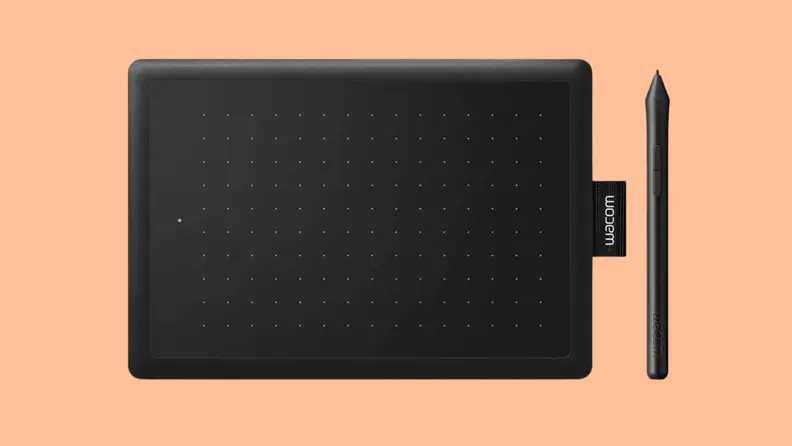 A Wacom One tablet against a peach color background.