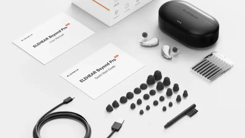 Hearing aids and accessories spread out on a white surface