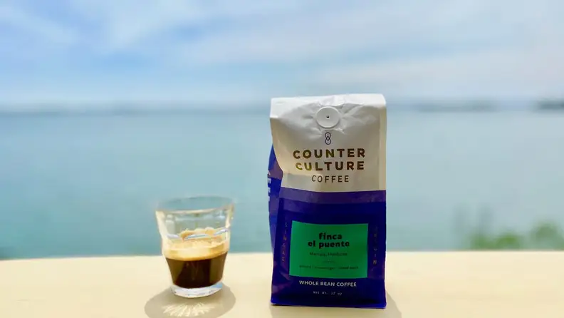 A cup of espresso next to a bag of Counter Culture Coffee beans