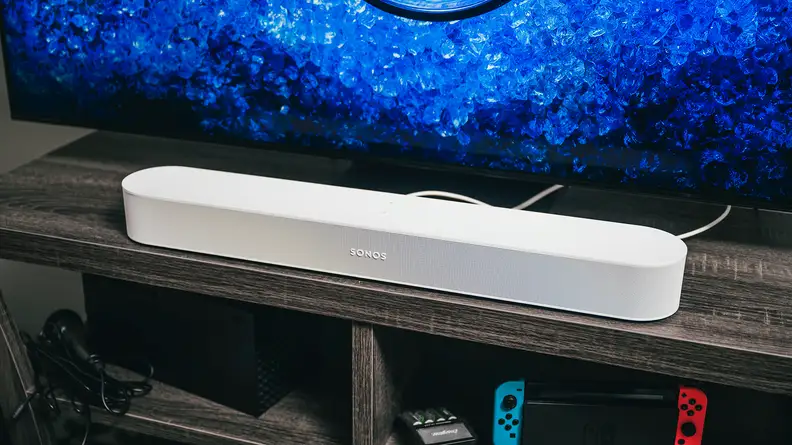 The Sonos Beam Gen 2 on a TV stand, in front of a TV playing content