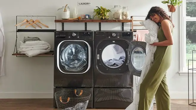 A person unloads a dryer full of laundry.