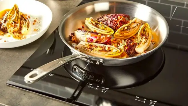 pan on stove burner with food. with plated meal next to it