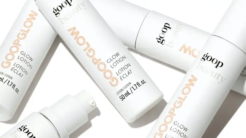 Several slim white bottles of moisturizer all laying on top of each other.