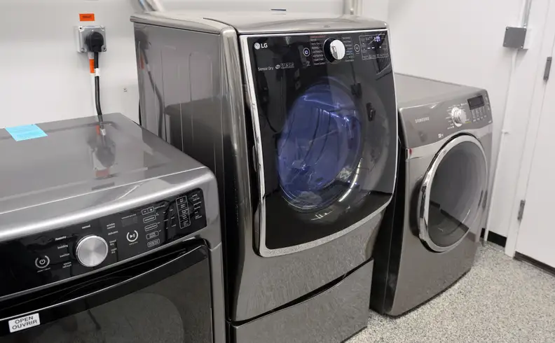 The LG DLEX5000V flanked by two conventional dryers, atop the WDP4V pedestal—which happens to feature a drawer for storage.