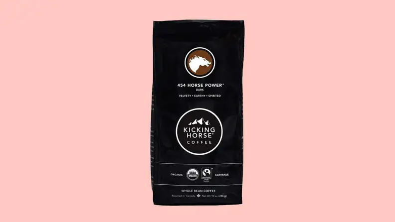 A bag of coffee grounds against a pink background.