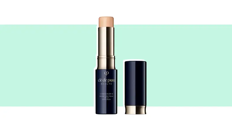 A tube of concealer against a green background.