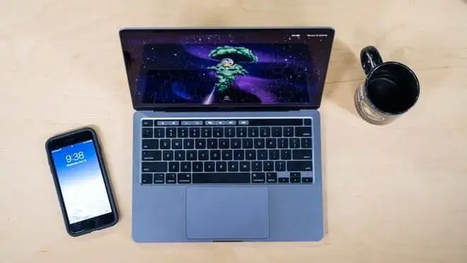 Laptop with phone and mug next to it