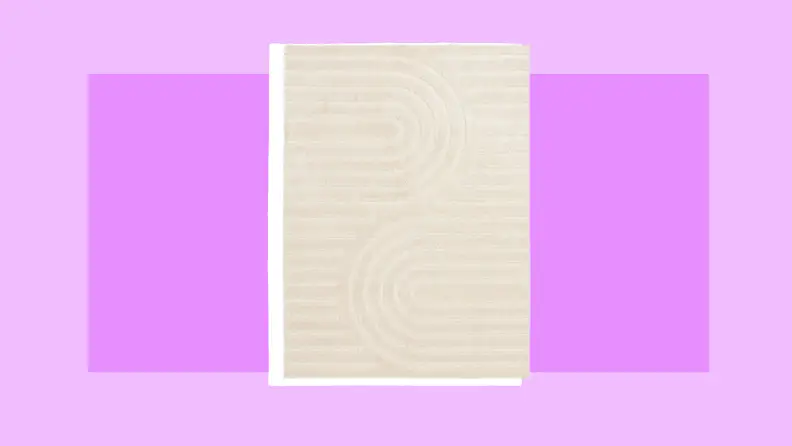 Cream colored rectangle area rug to place in a dorm room.