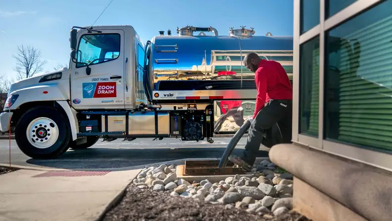 Technician operating a hose from a drain service truck