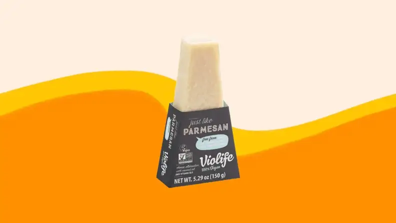A product photo of Violife Parmesan on an orange and beige background.