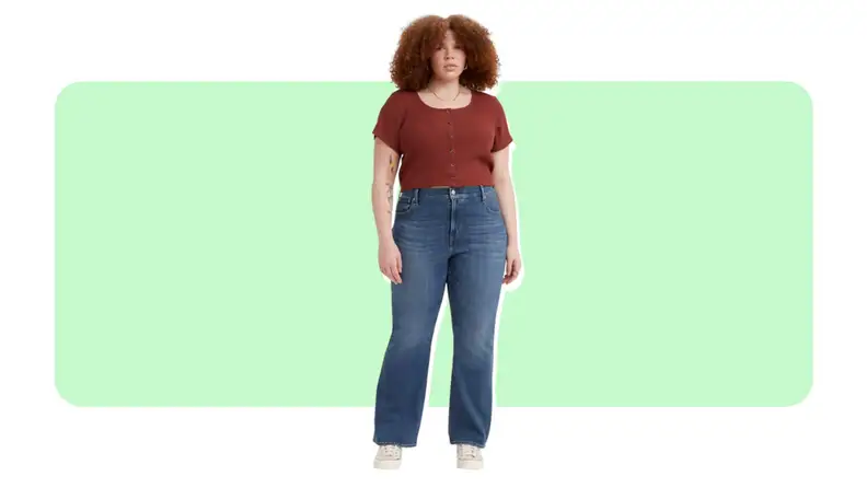 A model wears a pair of blue jeans with a slight bootcut leg and a red T-shirt.