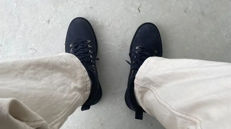 Pair of midnight navy Season Three hiking boots on man's feet.