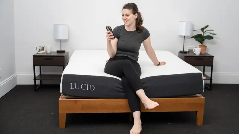 A person sitting on the bottom edge of the Lucid mattress.
