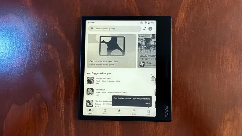 The Onyx Boox Page e-reader sits on top of wooden surface with black and white screen display turned on.