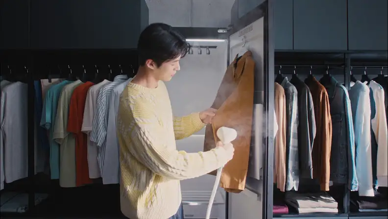 A person using the handheld steamer in the LG Styler.