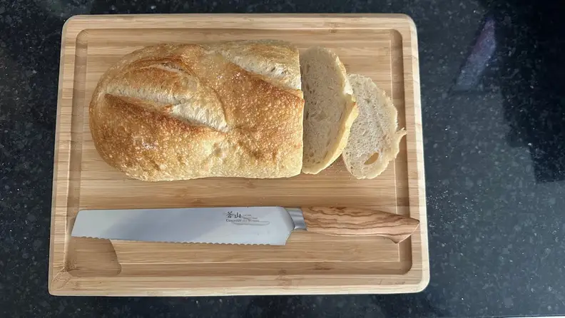 A loaf of bread and a Cangshan knife on a cutting board.