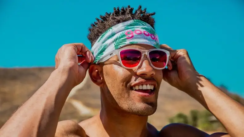 A man putting on pink sunglasses.