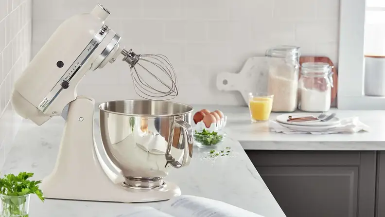 A beige stand mixer on a kitchen counter with its head tilted