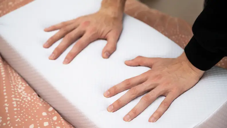 hands press into the surface of the pillow cube