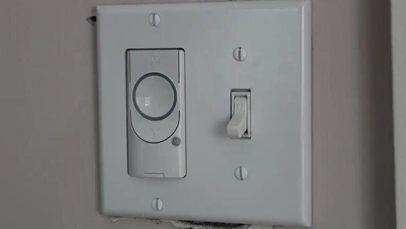 A white smart ceiling fan switch on a wall.