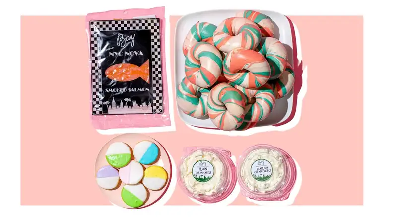 Multicolored mini bagels next to plastic containers of cream cheese from Baz Bagels.